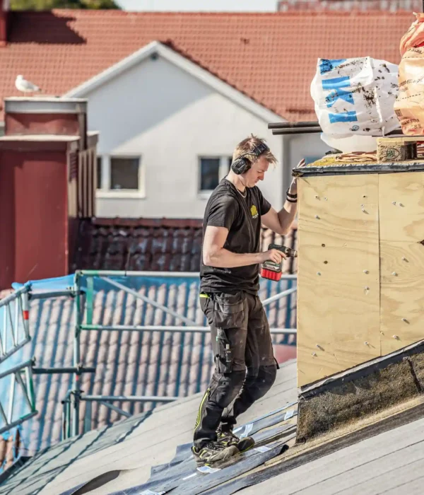 Medarbetare monterar plywoodskivor på fasad av takkupa